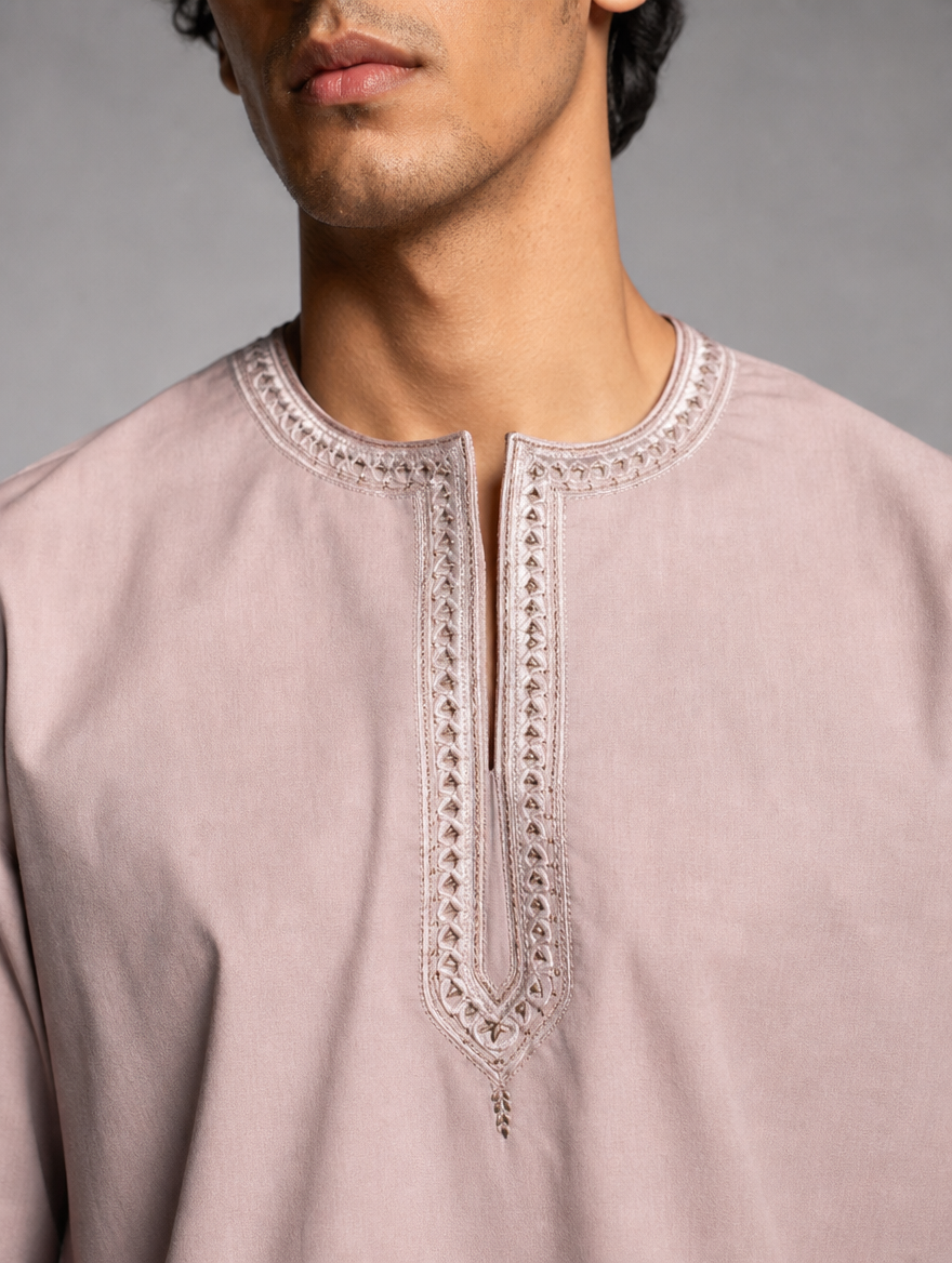 Upper torso view of men's dusty peach round neck short kurta with intricate embroidered trim around the neck and placket